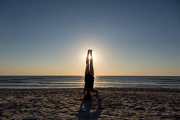 istock Young woman standing on her hands at the beach. 512403846