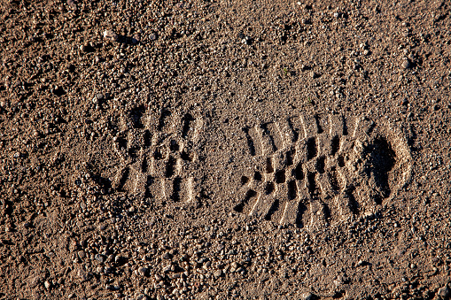 Shoe boot footprint in dry desert soil from hiking athlete.