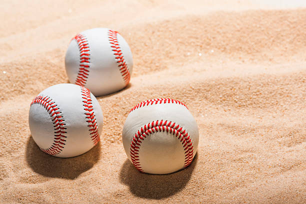 istock Three baseballs sitting in the sand at a beach 512407160