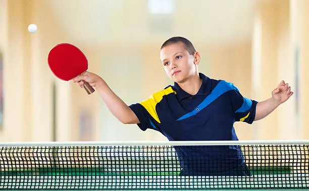 Portrait Of Kid with Racket Playing table Tennis in Action shot