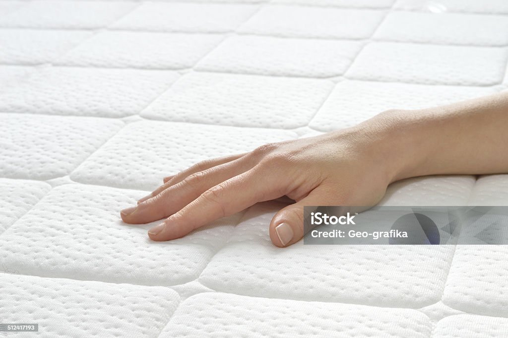 Choosing mattress and bed. Choosing mattress and bed. Close-up of female hand touching and testing mattress in a store. Copy space. Mattress Stock Photo