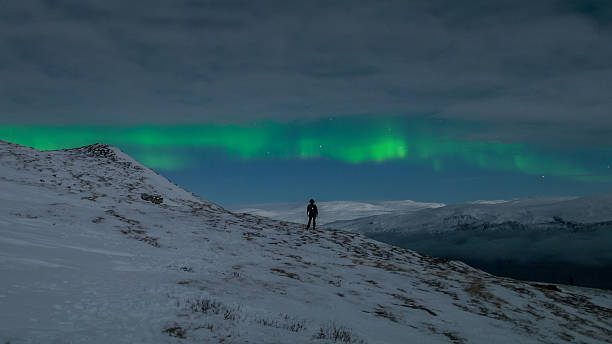 istock Woman watching northern lights alone on mountain 512417977