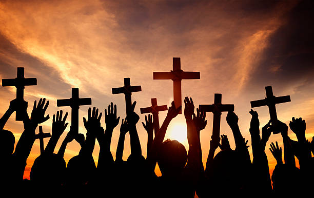 istock Group of People Holding Cross and Praying in Back Lit 512421423