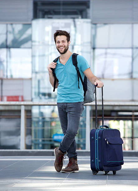 istock Young man smiling with bags at airport 512421949