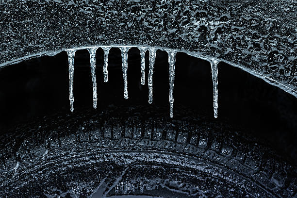Icicles on car near the lights and tires in snow at night