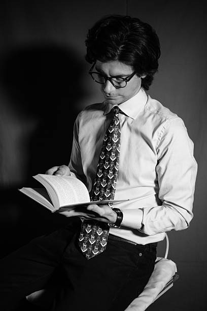 istock Young man reading a book with glasses 512434958