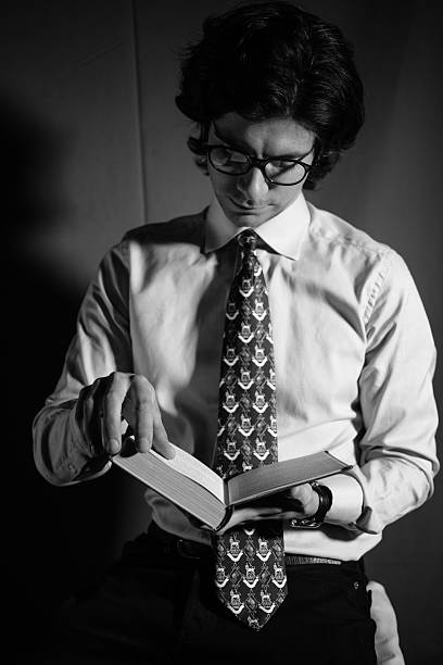 istock Young man reading a book with glasses 512435312