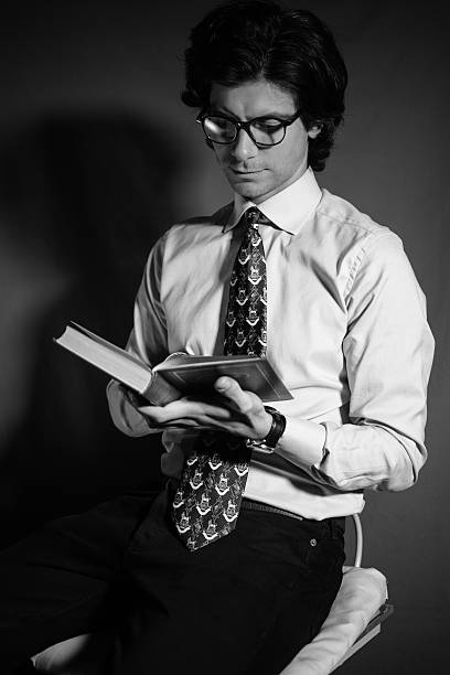 istock Young man reading a book with glasses 512435862