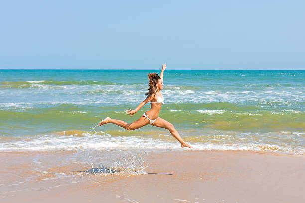 istock woman jumping on the beach 512450871