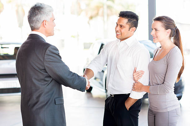 istock middle aged salesman handshaking with young couple 512451013