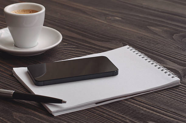 istock black smart phone on wooden dark background with notebook 512453510