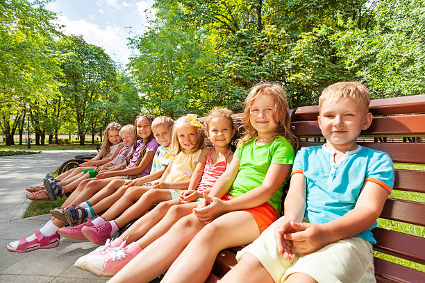istock Large group of kids sitting on the bench 512453971