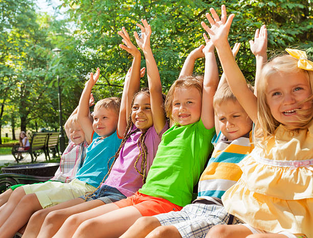 istock Happy cheering kids lifting hands on the bench 512453987