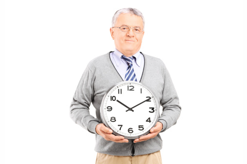 Senior gentleman holding a big wall clock isolated on white background