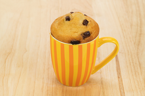 A baked in a mug chocolate chip cupcake placed onto a table