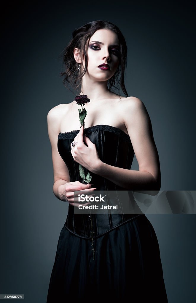 Portrait of beautiful goth girl holding withered flower in hands Portrait of beautiful goth girl holding a withered flower in hands Adult Stock Photo