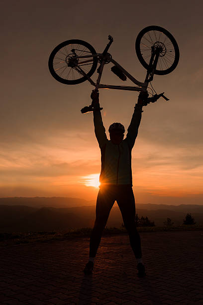 istock Adult Man Lifting his Bicycle at Dusk 512460452