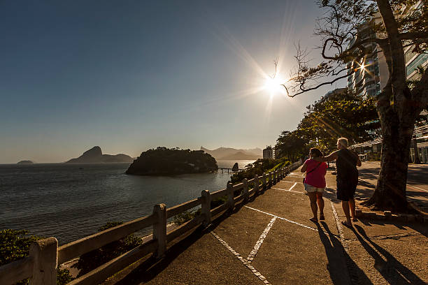 virent couple marchant au coucher de soleil sur la côte - niteroi photos et images de collection