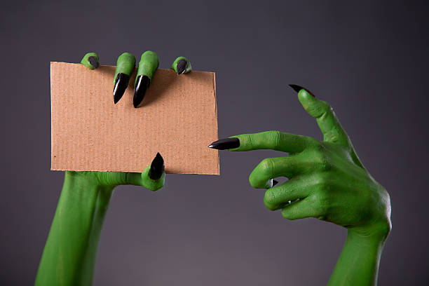 istock Green monster hands with black long nails pointing on cardboard 512472064
