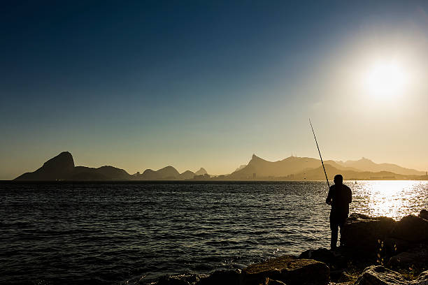 homme de pêche dans la baie de guanabara au coucher du soleil - sugarloaf mountain flash photos et images de collection