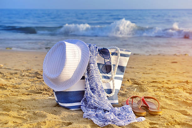 istock Hat, bag, sun glasses and flip flops on  sandy beach 512473818