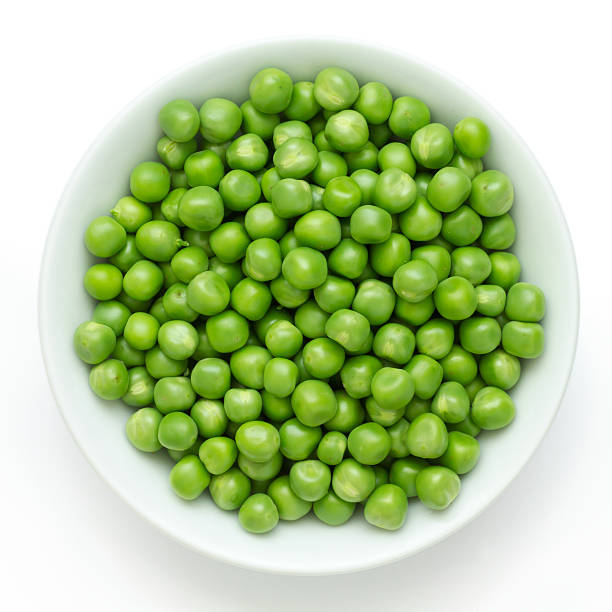 Fresh garden peas in a ceramic dish shot from above.