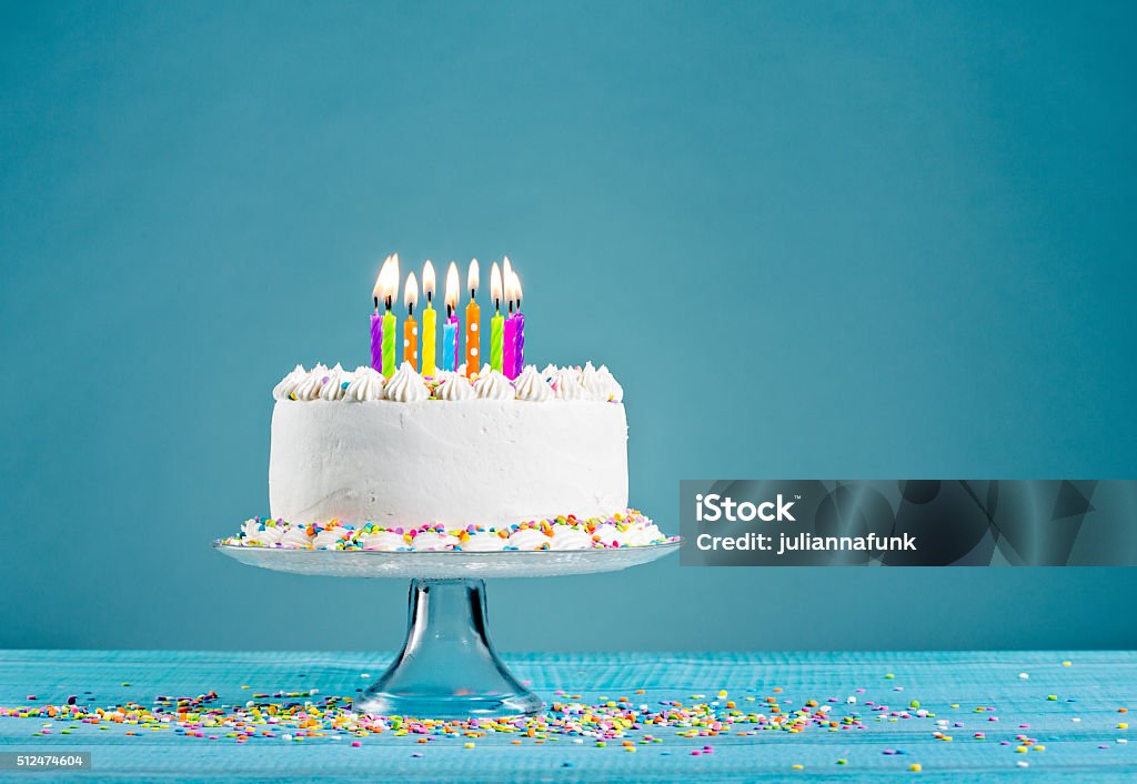 Birthday Cake with Candles White Buttercream icing birthday cake with with colorful sprinkles and Candles over blue background Birthday Cake Stock Photo
