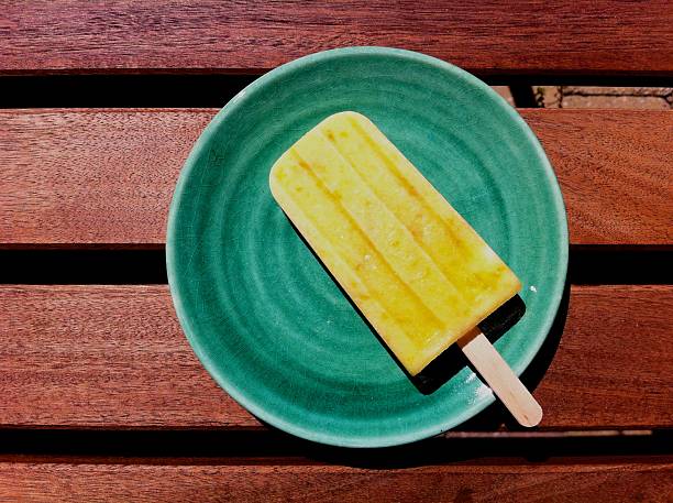 Homemade mango-peach popsicle on plate on table