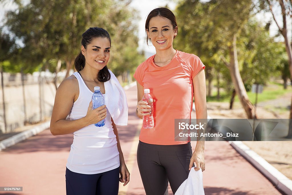 Beautiful girls drinking water Portrait of a couple of cute young women in sporty outfits holding a bottle of water Adult Stock Photo