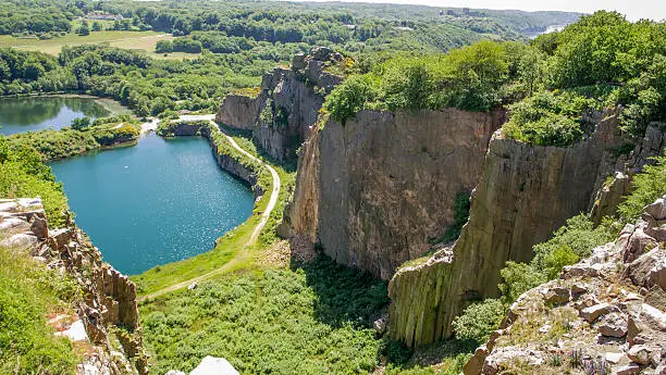 Former granite quarry on Bornholm, the steep sides now a paradise for sea gulls. A climber is rappelling down the cliff side (right) for scale. In the background is the old castle ruin Hammershus.