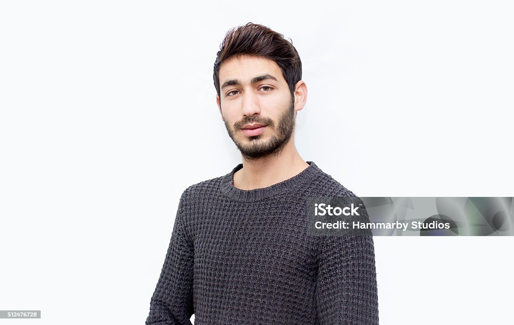 Portrait of young man over isolated on white Portrait of young man over isolated on white. Young man standing over white background and looking at camera with blank facial expression. Horizontal composition. Young man wearing a gray sweater. Front view, studio shot, developed from RAW format. Young man looking at camera with serious facial expression has got short brown hair and short beard. Young man's ethnicity belongs to Turkish ethnicity, middle eastern ethnicity. Focus on man. Cut Out Stock Photo