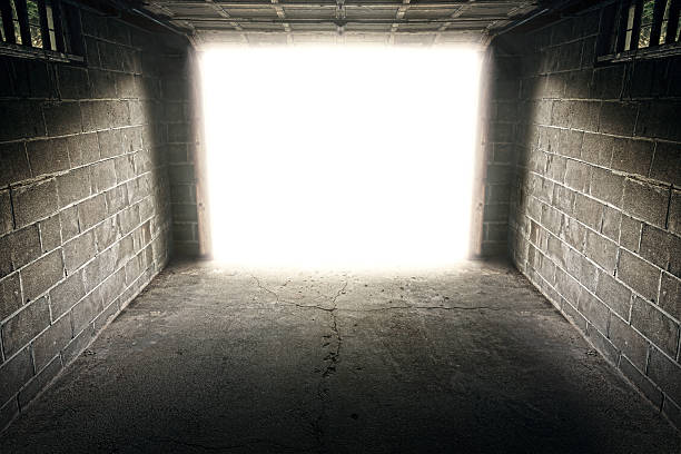 istock Interior of grungy garage looking out to a bright light 512488346