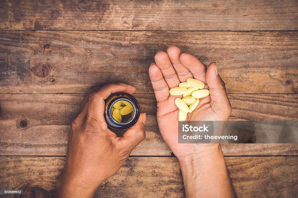 Botella de verter píldoras en un hombre de mano - Foto de stock de Píldoras libre de derechos