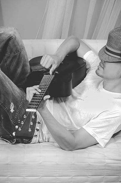 istock asian guitarist lying & playing acoustic guitar, vintage BW filter 512489812