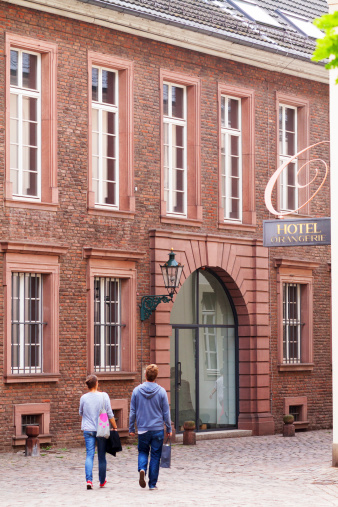 Düsseldorf, Germany - September 6, 2014: Capture of city museum Stadtmuseum in Düsseldorf. Two people are walking along street Bäckerstraße in summer. At right side is sign of hotel.