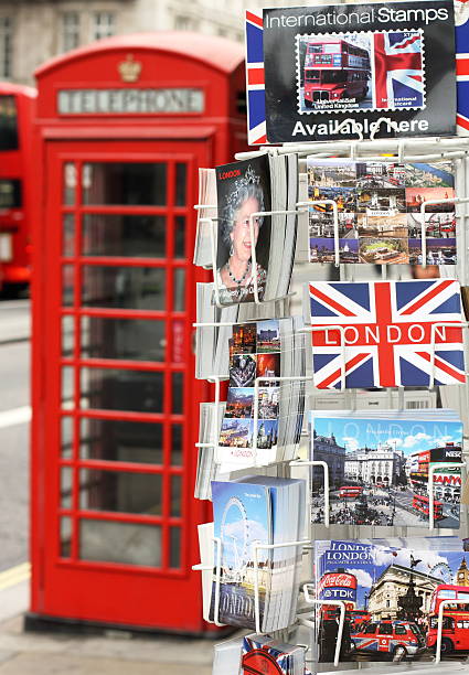 Postcards of London London, England - Sept 11, 2014: A display stand of postcards in a central London Street with scenes of London and the British Queen. In the background is a red telephone box and part of a red bus. London Memorabilia stock pictures, royalty-free photos & images