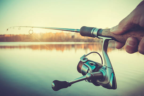 istock hand with spinning and reel on the evening summer lake 512510484