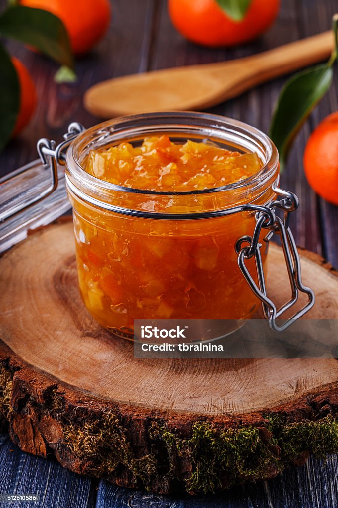 Orange (tangerine) jam in a glass jar on the table. Orange (tangerine) jam in a glass jar on the table, selective focus. Breakfast Stock Photo