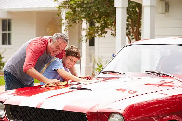 Photo of Grandfather And Grandson Cleaning Restored Classic Car