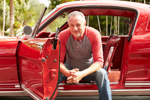 Retired Senior Man Sitting In Restored Classic Car Smiling To Camera