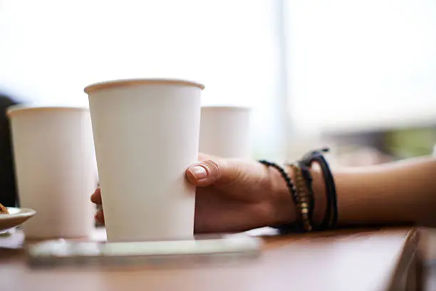 Female hand holding disposable cu of coffee