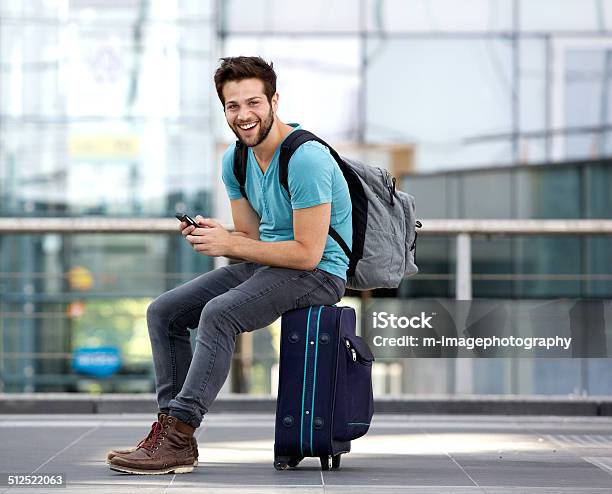 Man Sitting On Suitcase And Sending Text Message Stock Photo - Download Image Now - Men, Airport, Travel