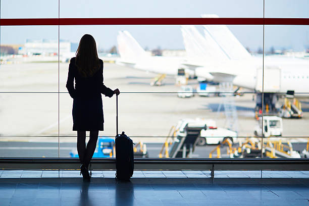 Young woman in the airport Young woman in the airport, looking through the window at planes business travel stock pictures, royalty-free photos & images