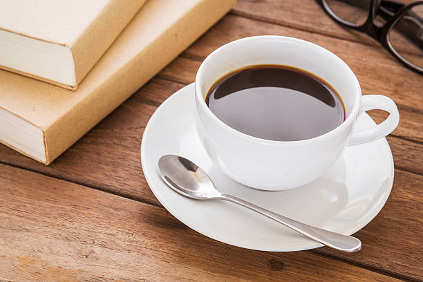 istock Coffee cup and book on wooden table 512522875