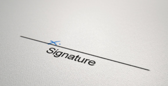 A white paper with a black line printed in ink showing the area for a signature to be signed and indicated with a hand written x