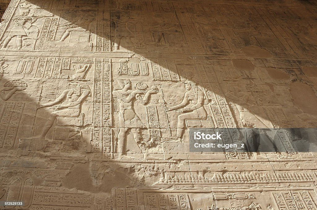 Reliefs on the walls of the Temple of Edfu. Egypt. The Temple of Edfu is an ancient Egyptian temple located on the west bank of the Nile in the city of Edfu which was known in Greco-Roman times as Apollonopolis Magna, after the chief god Horus-Apollo. It is one of the best preserved temples in Egypt. The temple, dedicated to the falcon god Horus, was built in the Ptolemaic period between 237 and 57 BC. God Stock Photo