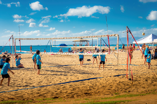 Waikiki Beach Area, Honolulu, Hawaii, USA - December 11, 2015: Local school children playing beach volleyball on a sunny mid-afternoon outing. Image taken adjacent to Kuhio Beach Park, Waikiki Beach Area.