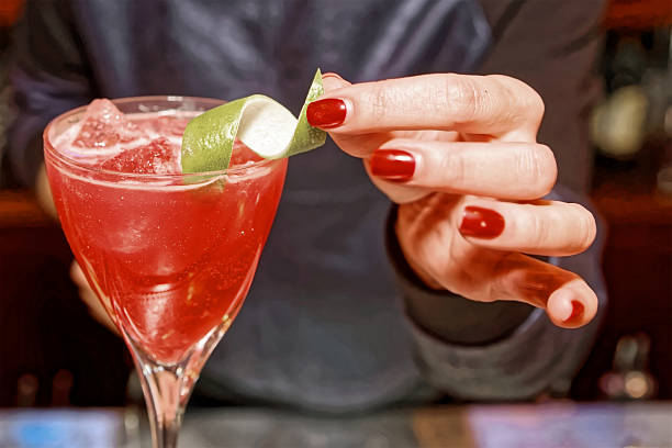 istock Female bartender is adding citrus zest to cocktail, toned 512537078