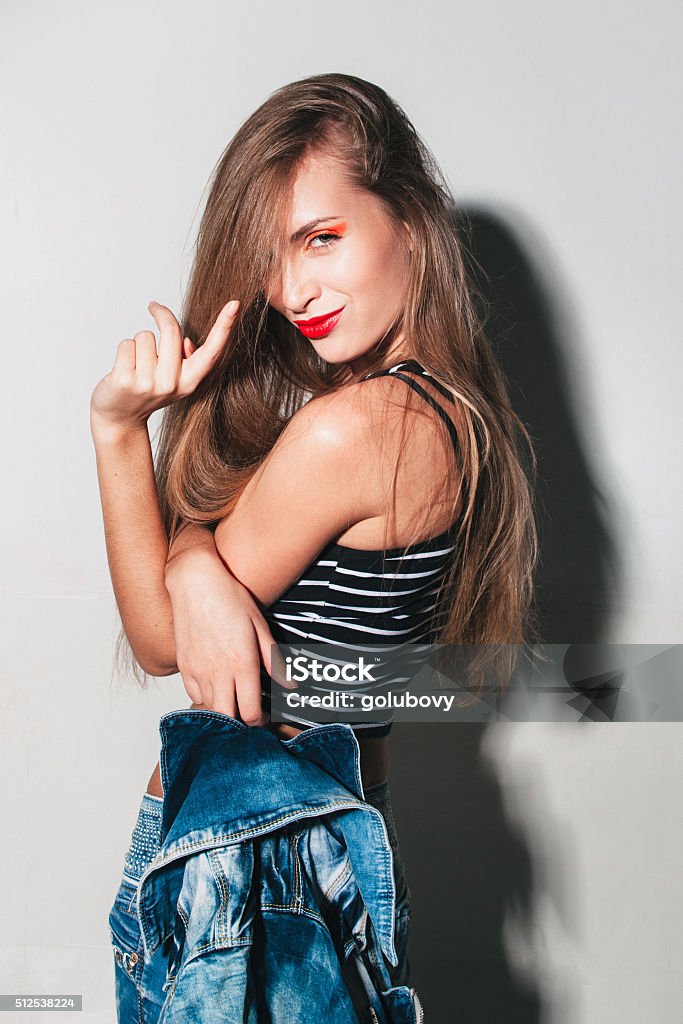 daring girl with bright makeup beckoning daring girl with bright makeup beckoning. Girl on a white background in a new collection of denim After Party Stock Photo