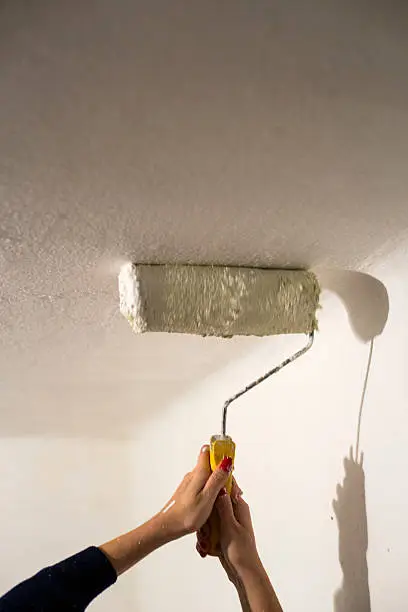 A wall being painted with a paint roller.